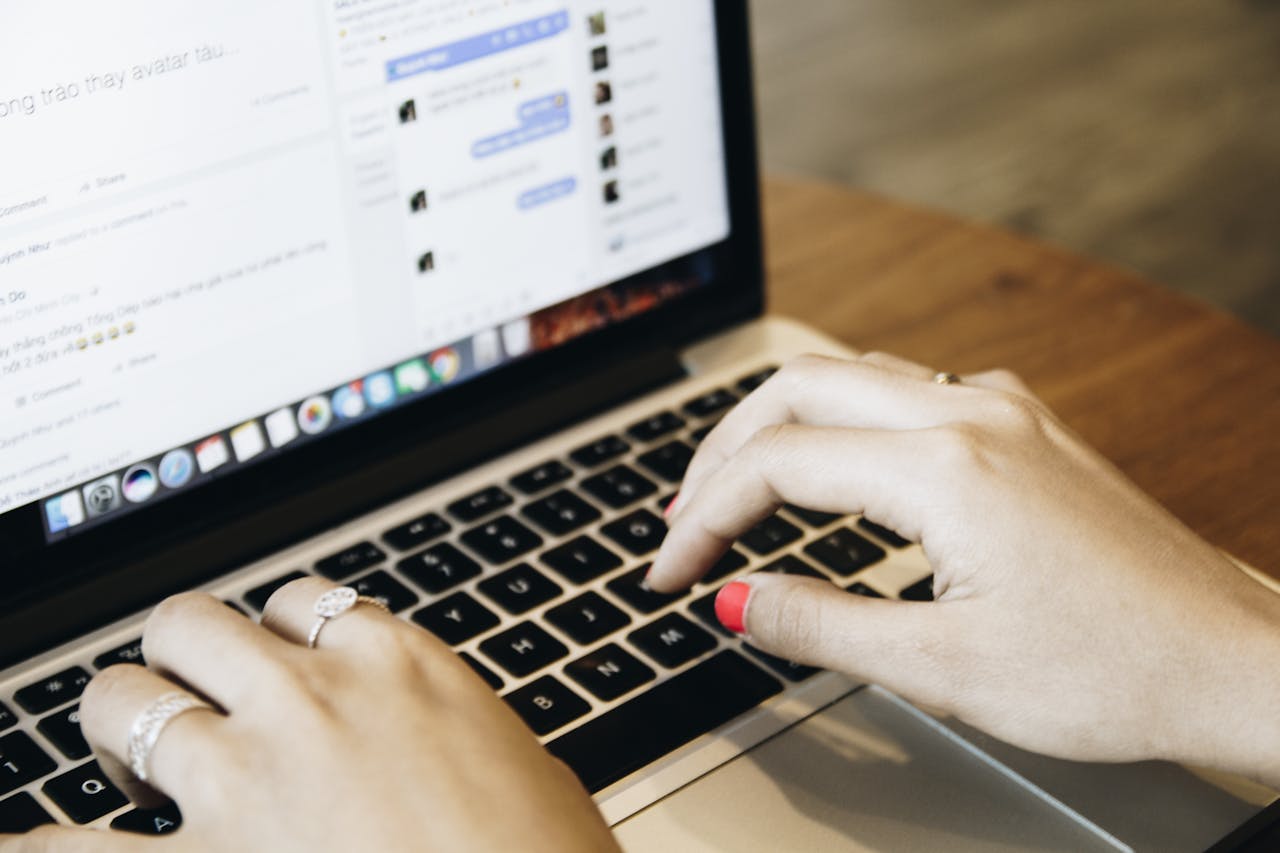 Close-up of hands typing on a laptop keyboard with a messaging app open on the screen.